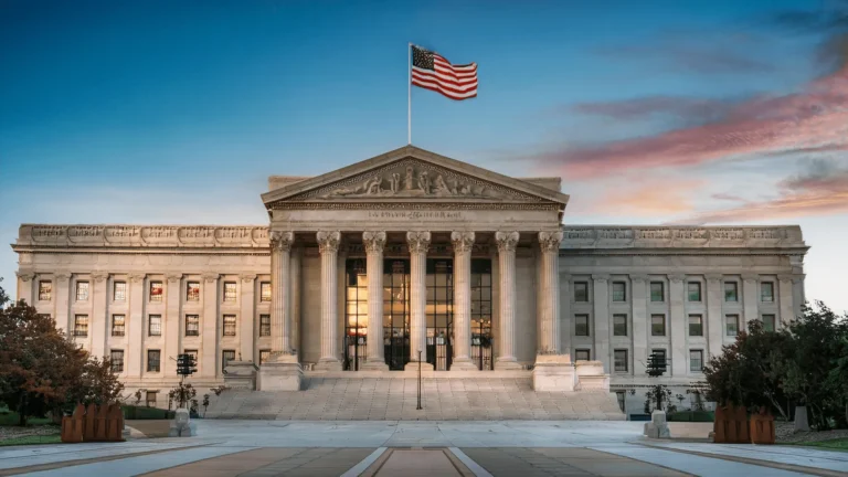 Monumentalny neoklasyczny budynek administracji miejskiej i powiatowej w Denver z flagą USA na tle nieba o zachodzie słońca.
